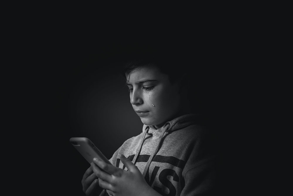 Photo of child looking at phone and crying